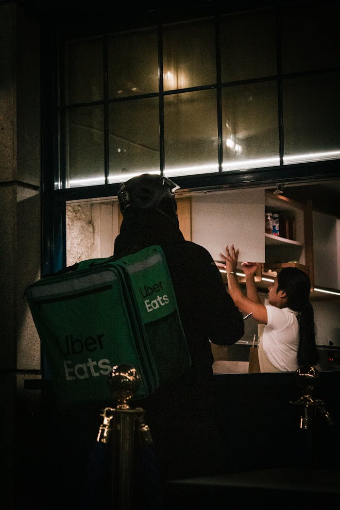 An Uber Eats courier picks up food from a restaurant at night.